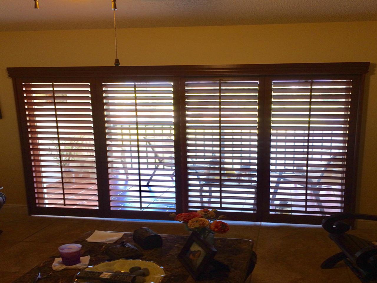 Stained wood interior shutters on double sliding glass doors