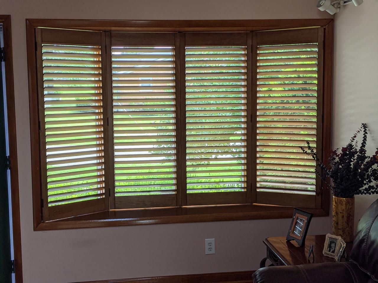 stained wood shutters with hidden tilt rod on bay window