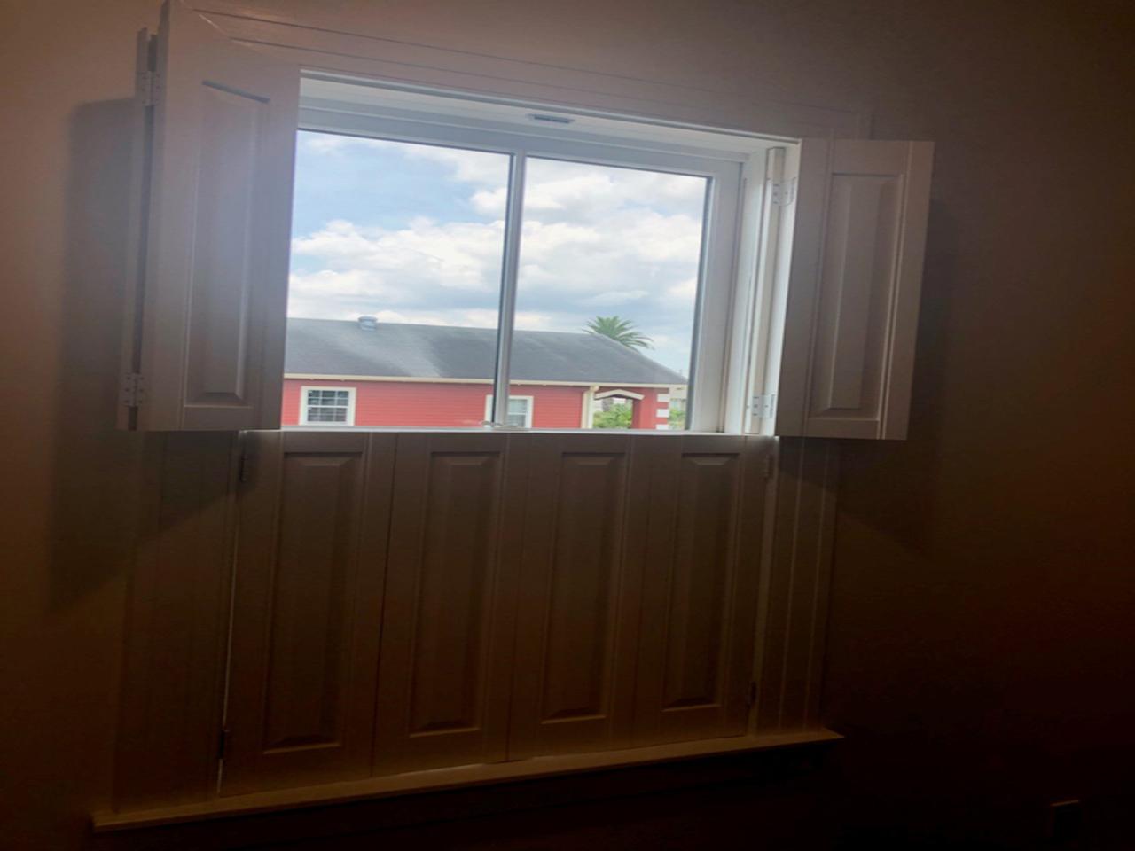 Raised panel shutters on a window with top shutters opened