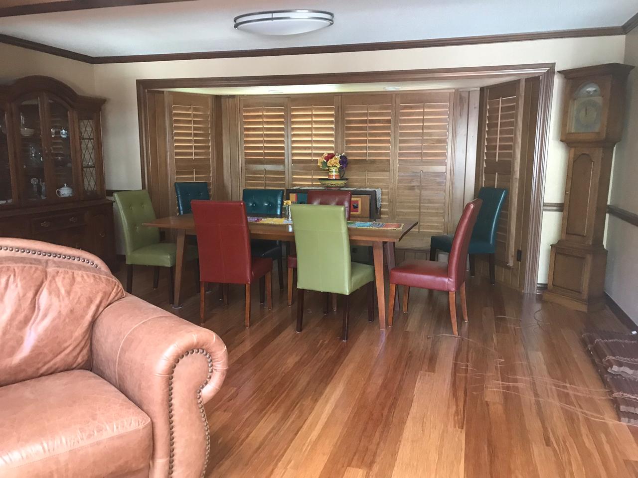 Open concept area with stained shutters on the bay window by the dining table